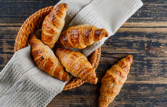 croissant-in-basket-with-cloth-on-wooden-table-flat-lay