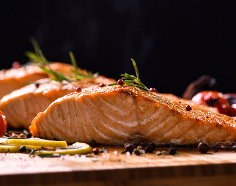 grilled-salmon-fish-and-various-vegetables-on-wooden-table-on-black