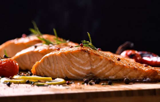 grilled-salmon-fish-and-various-vegetables-on-wooden-table-on-black